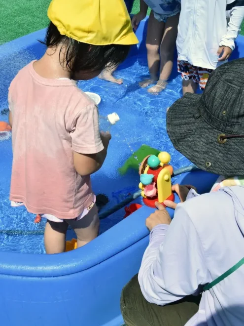 コローレ手稲が運営する児童発達支援事業所で、職員と水遊びを楽しむ子ども＝札幌市手稲区