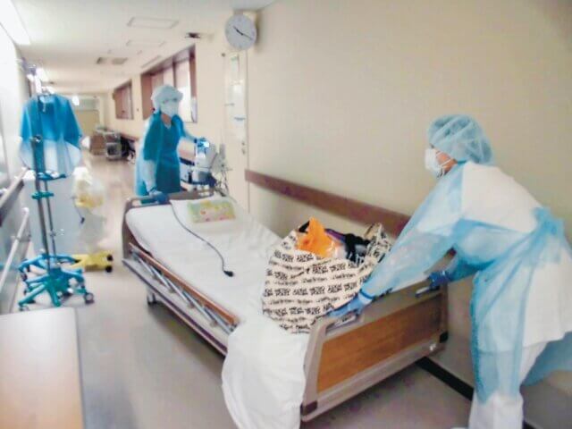 産科病棟内で、感染妊婦のベッドを運ぶ看護師たち。防護具などフル着用のため、すぐ汗だくに（北大病院提供）