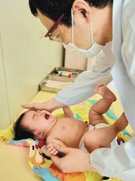旭川市保健所で行われた4カ月児健診で、体を触って発育状況を確認する医師