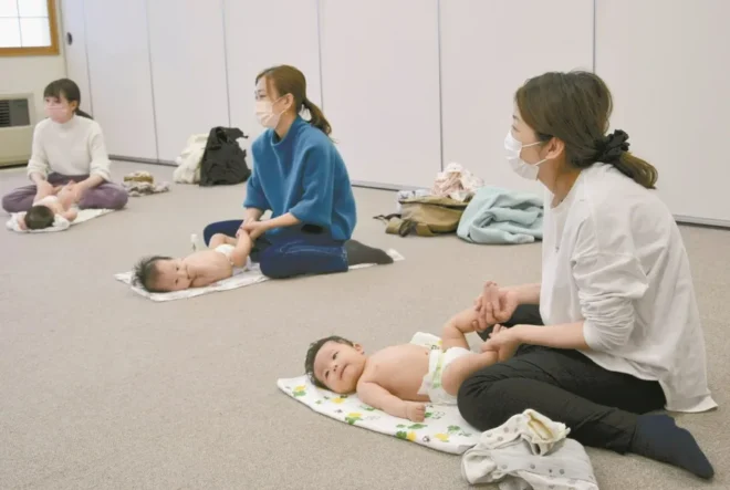 「ベビーマッサージ」で赤ちゃんの体を優しくさする参加者