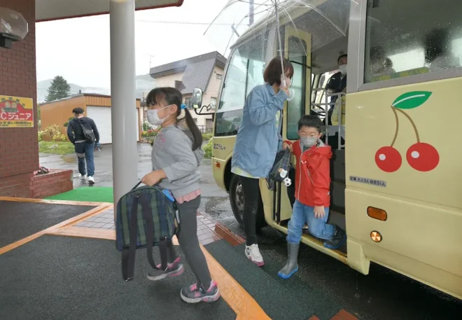 職員に見守られながら通園バスを降りる札幌みすまい幼稚園の園児たち（植村佳弘撮影）