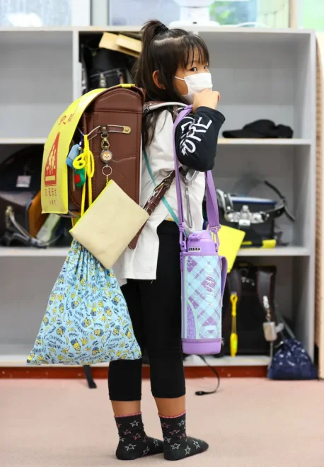 ランドセルに加え、水筒や着替えなど多くの荷物を持つ小学1年生＝6月、札幌市内の児童会館