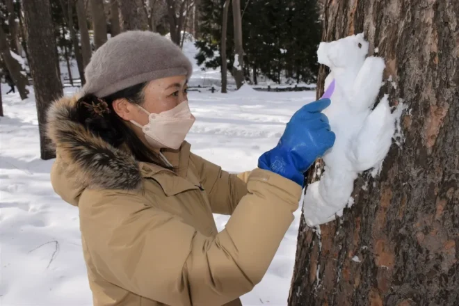粘土工作に使うへらで雪を削り、リスを形づくる田中宏美さん
