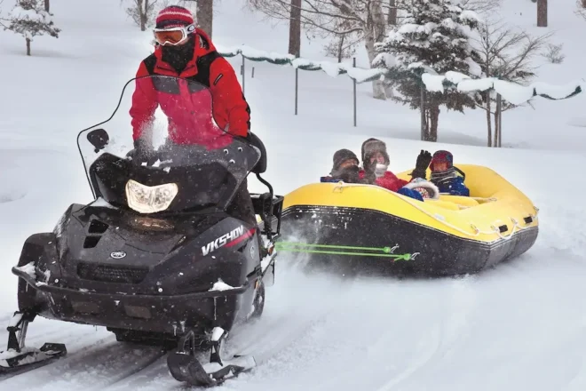 雪原をスノーラフティングで駆け抜ける家族連れ