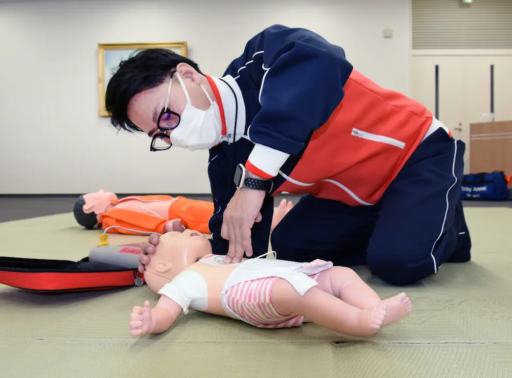 乳児の人形を使って胸骨圧迫の方法を説明する永沢貴博さん
