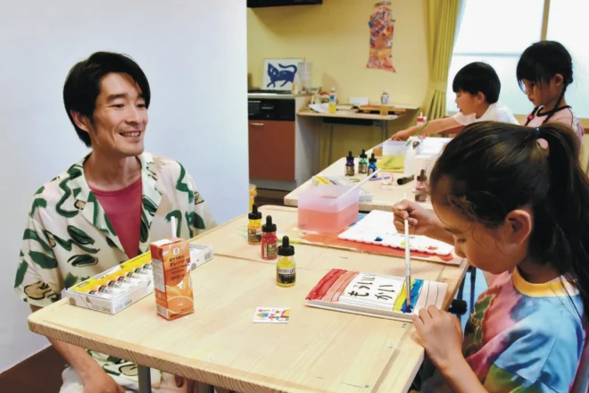 絵本作りに励む児童を見守る杏南さん（左端）