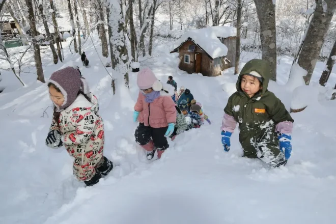 「北清の森」で小屋のある広場から深雪をこいで斜面を登る恵庭幼稚園の子どもたち（小室泰規撮影）
